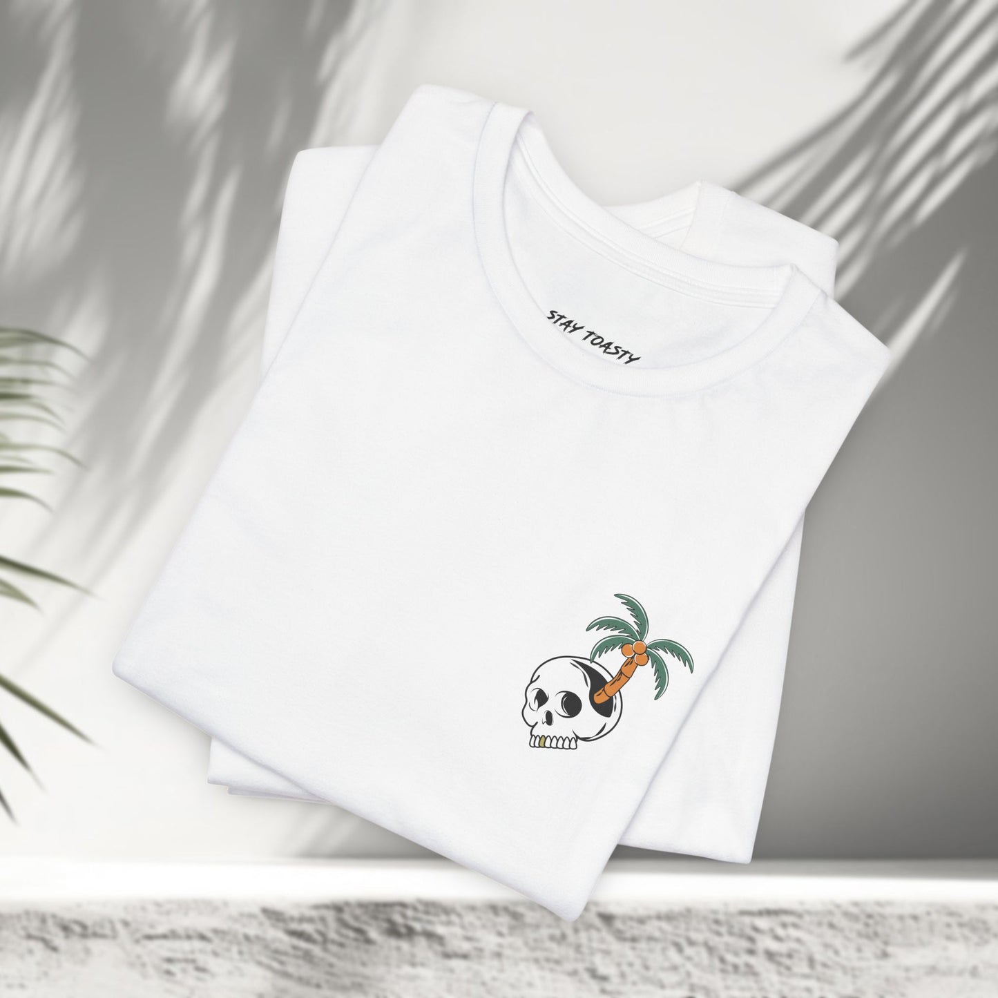 Folded white Paradise State of Mind tee showing small skull and palm tree front chest logo