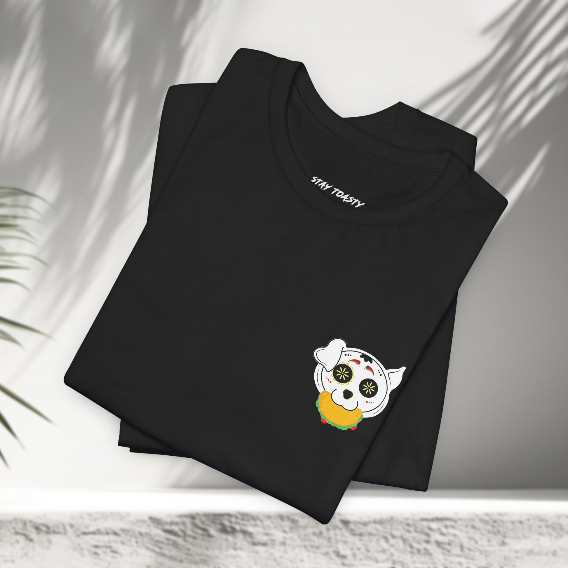 Black Tacos and Doggos tees folded showing small sugar skull dog and taco chest print
