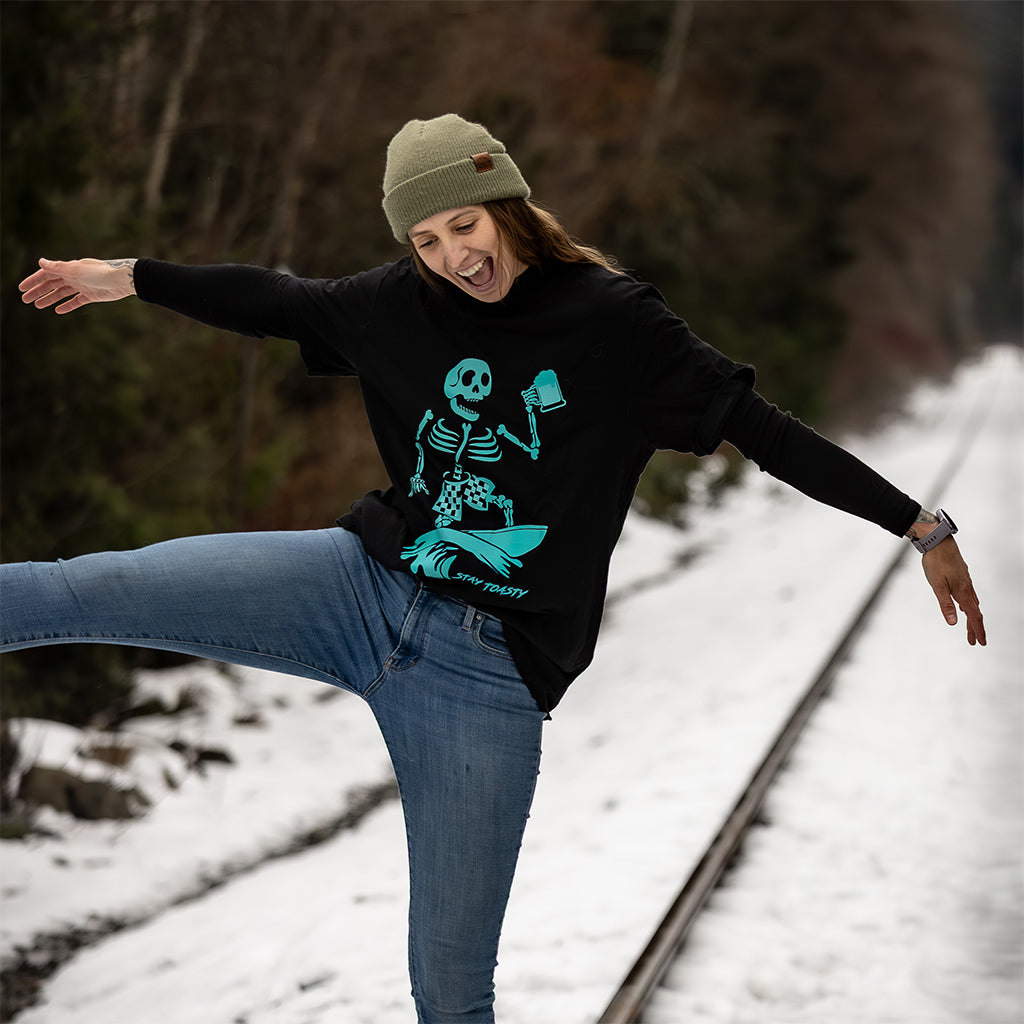 Woman balancing on train tracks wearing black Party Wave graphic tee in winter setting