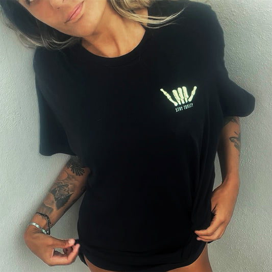 Woman wearing a black oversized T-shirt with yellow skeleton shaka graphic and ‘Stay Toasty’ text