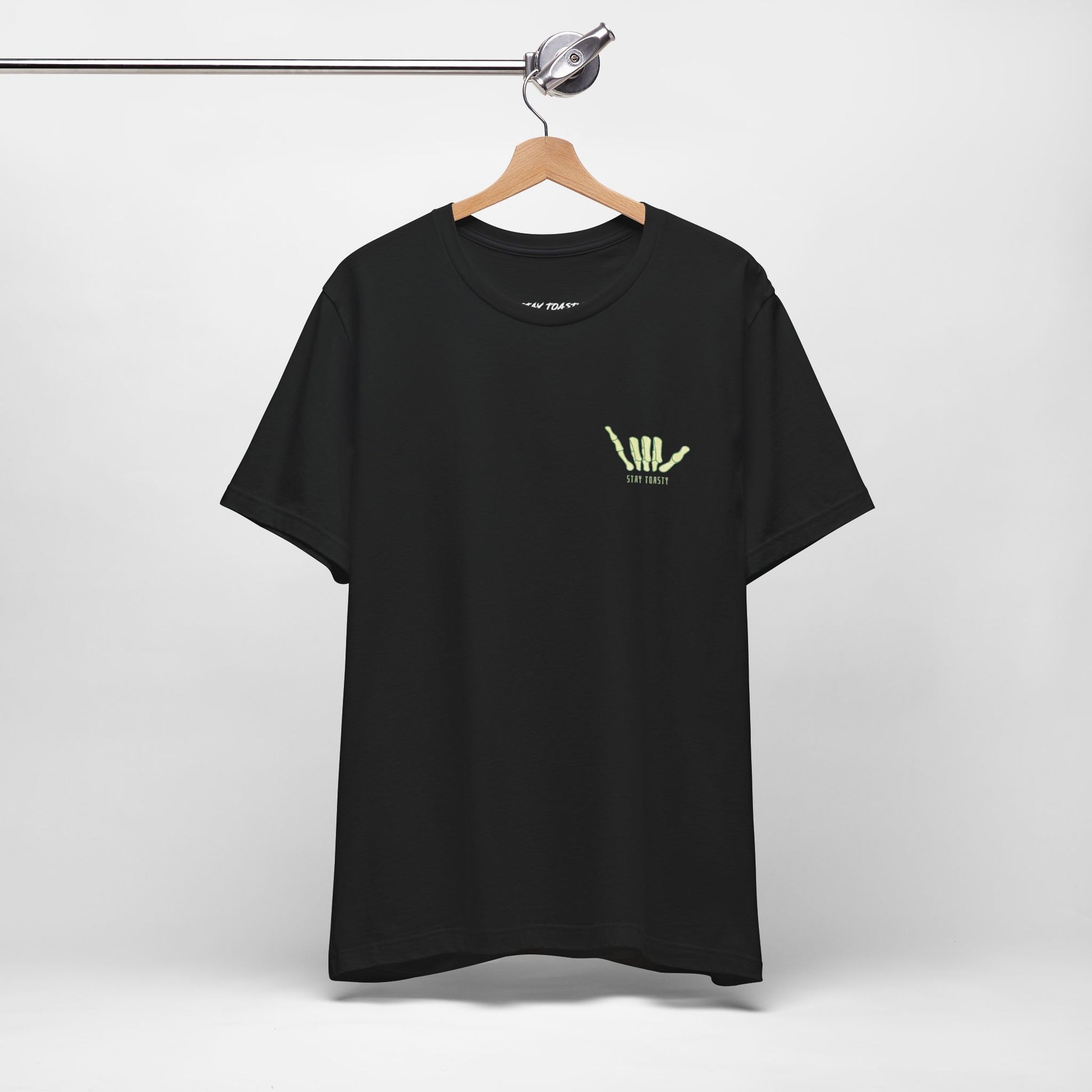 Black T-shirt with yellow skeleton shaka graphic and text on hanger against white background.
