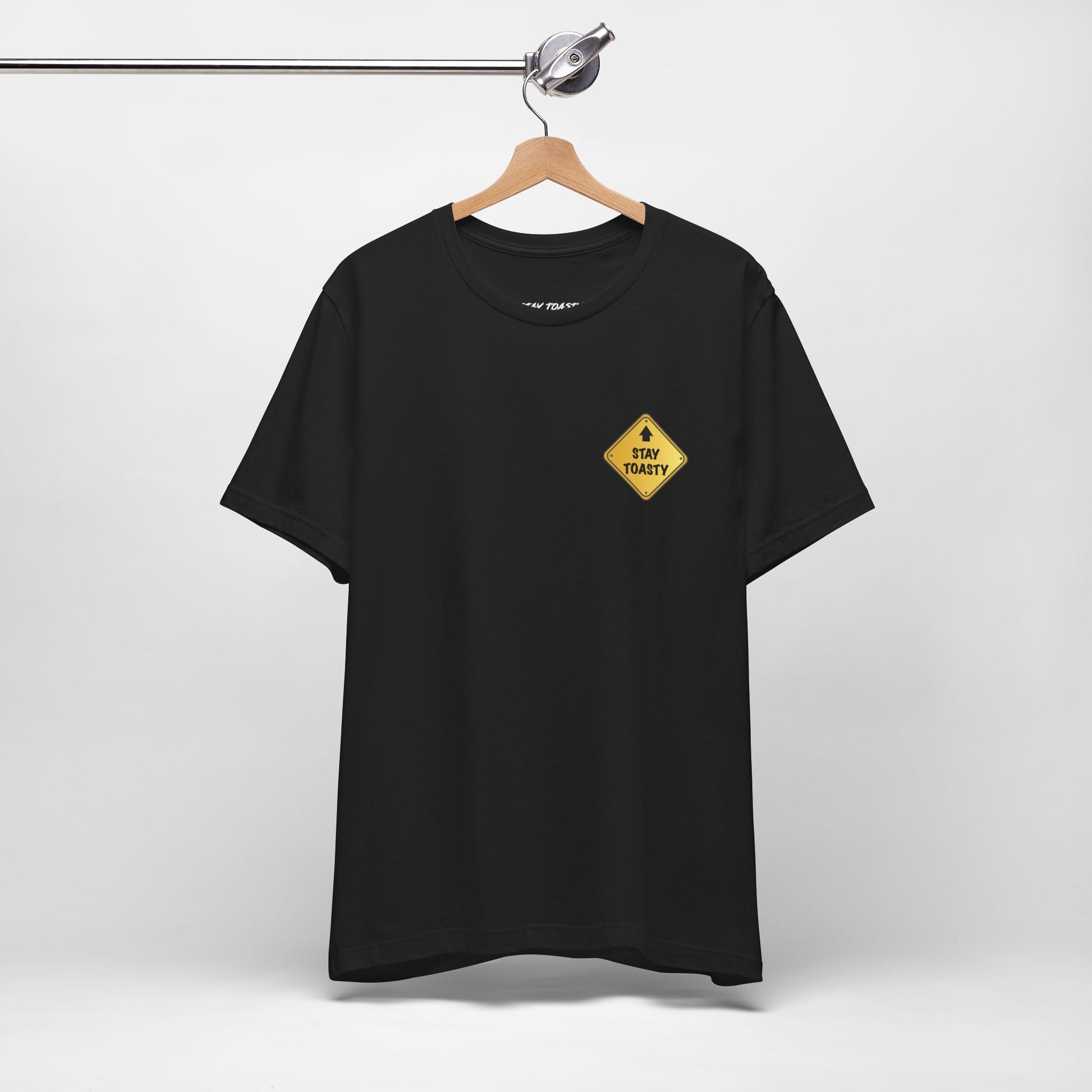 Hanging black t-shirt with a yellow street sign graphic on front cheast with text "Stay Toasty". 