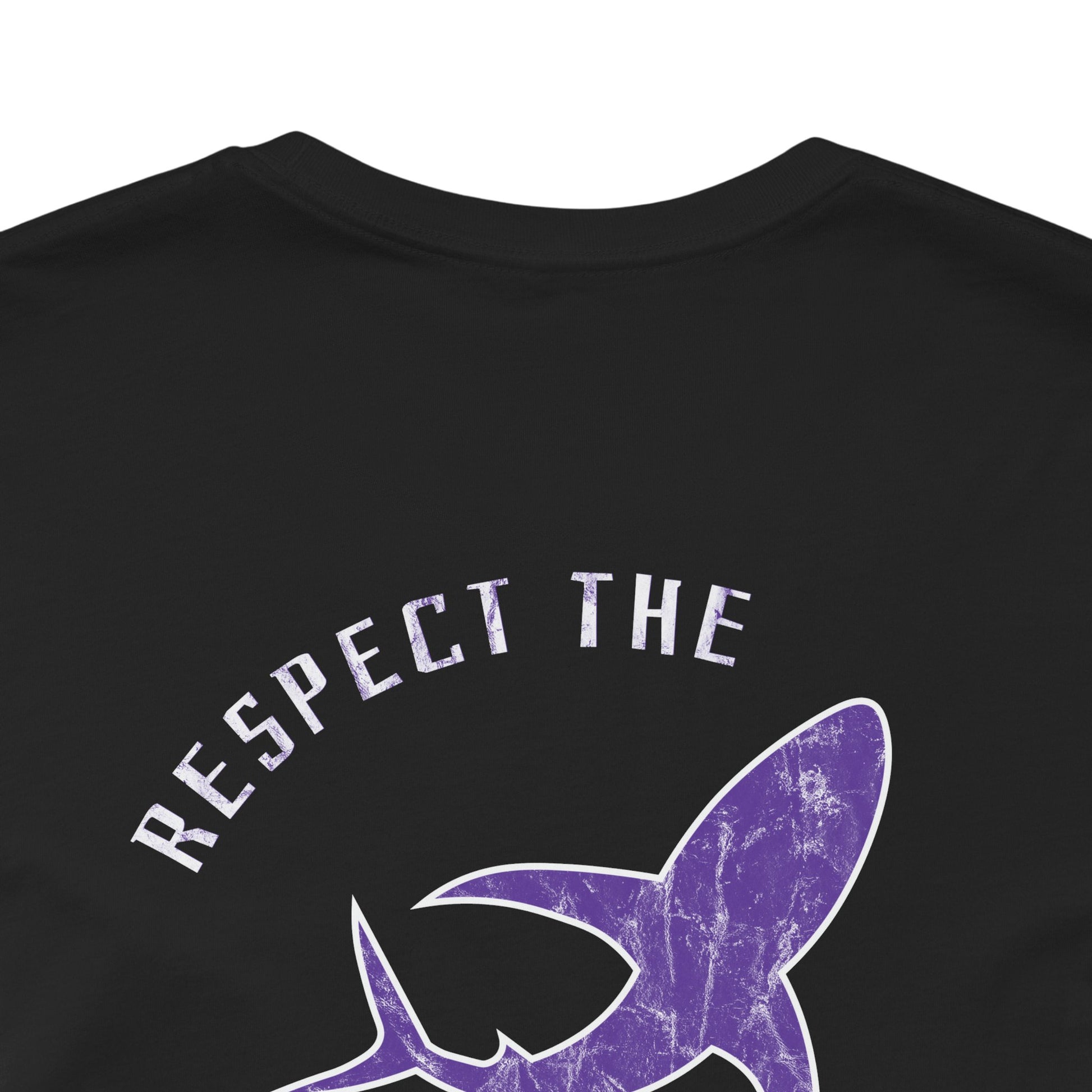 Black graphic tee with text "Respect the Locals" text around a shark graphic. Purple design with marble finish. Back close-up view.