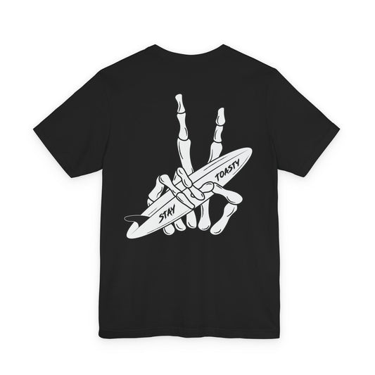 A black graphic t-shirt with a back graphic of a skeletal hand peach sign holding a surfboard, featuring the words 'STAY' and 'TOASTY'.