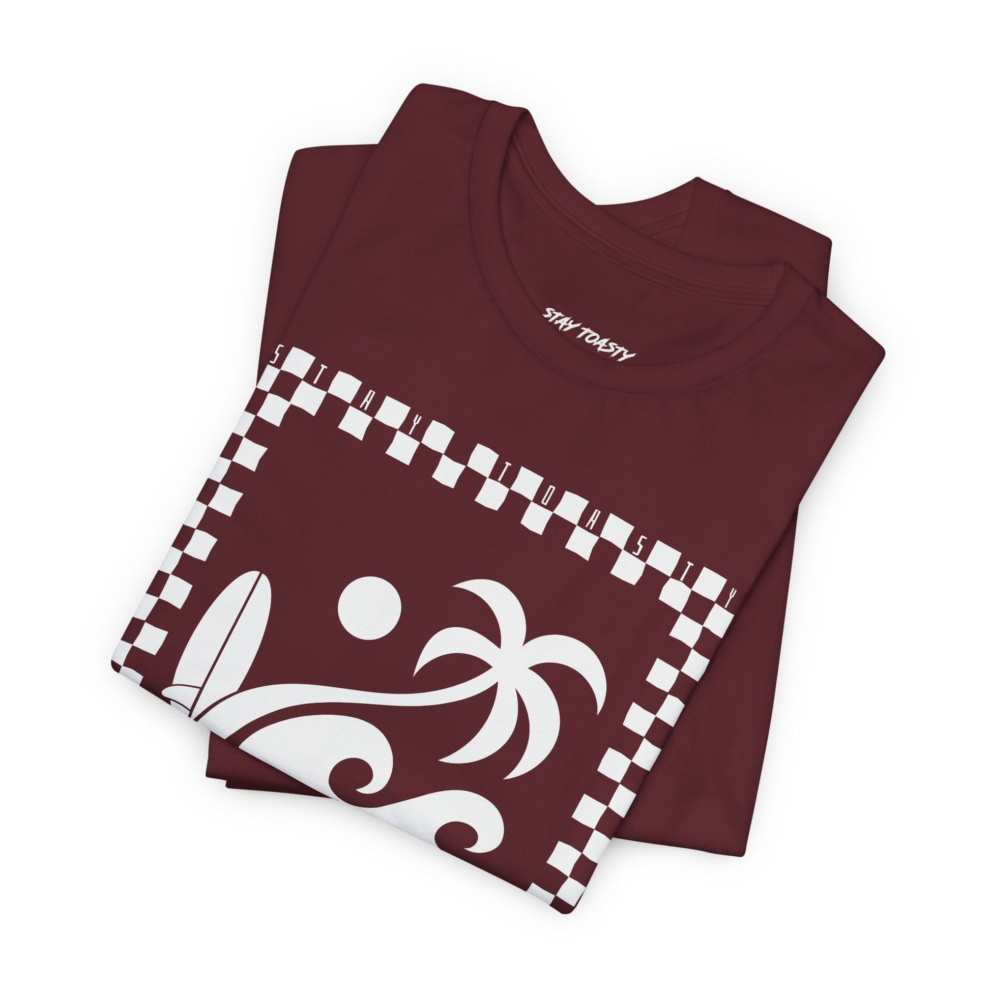 Folded maroon graphic tee with surf beach graphics with 'SALTY DAZE' text and 'Stay Toasty' inside of a checkered outline.