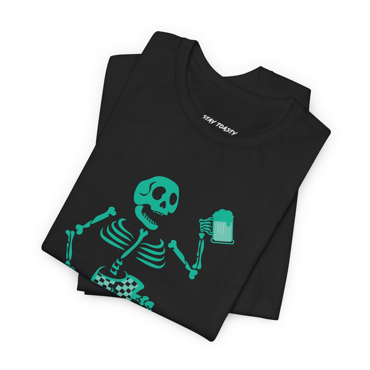 A folded black t-shirt featuring a bright teal-green skeleton graphic holding a beer, with the brand name 'stay toasty' 