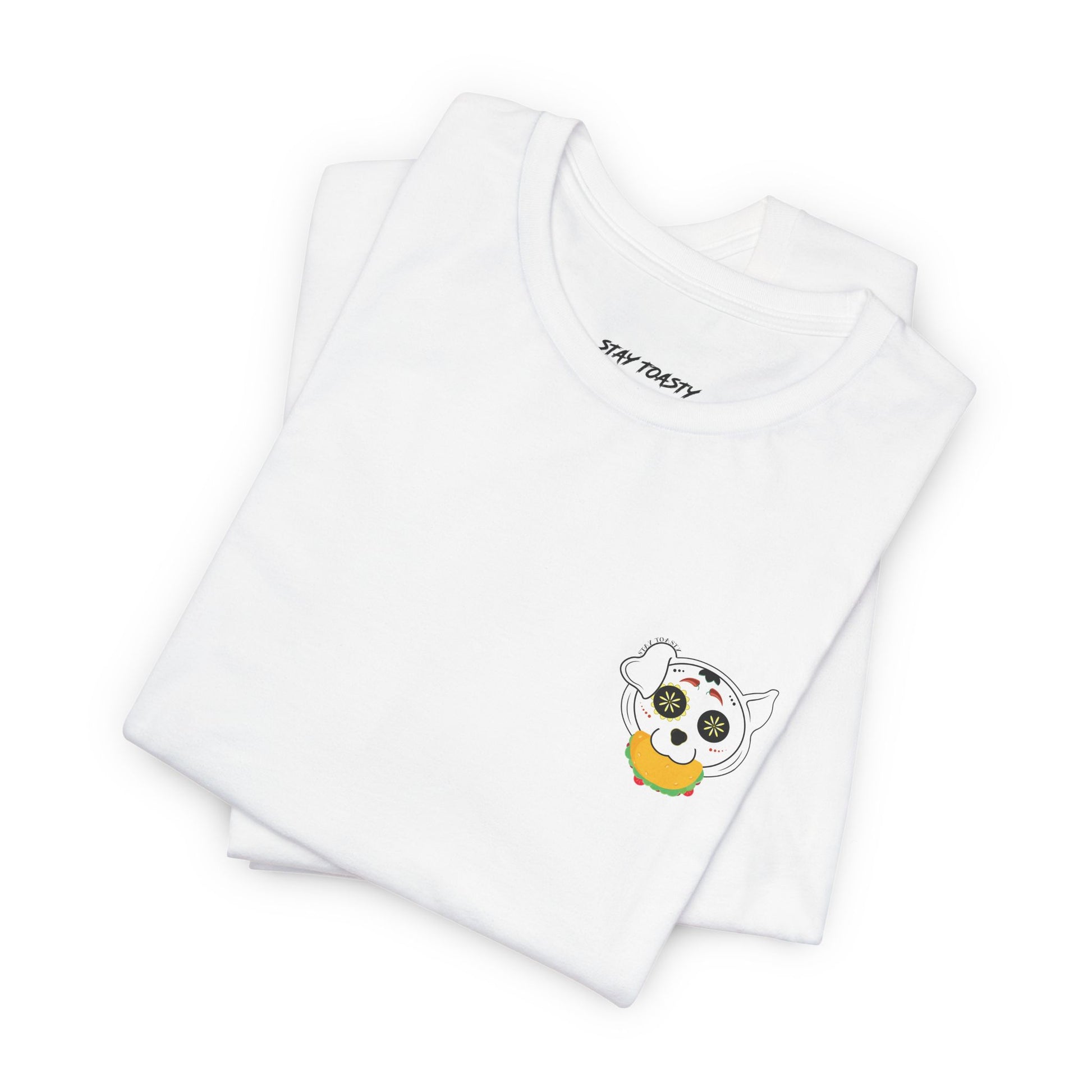 Folded white tee with front chest graphic of a sugar skull dog with a taco in his mouth. Design by Stay Toasty.
